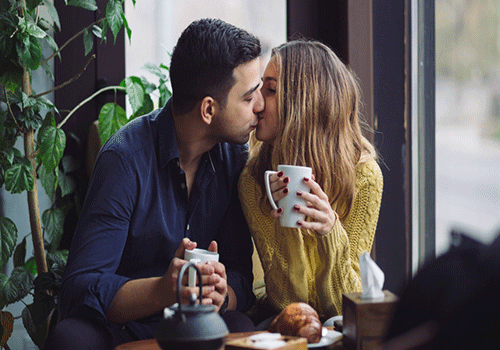 homem e mulher na cafeteria se beijando após se conhecerem em aplicativos para namoro